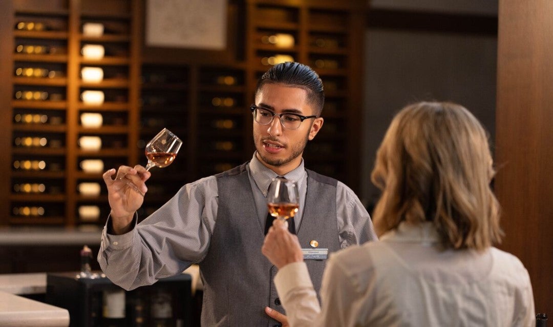 Young man raises a glass of wine to demonstrate its features to a guest.