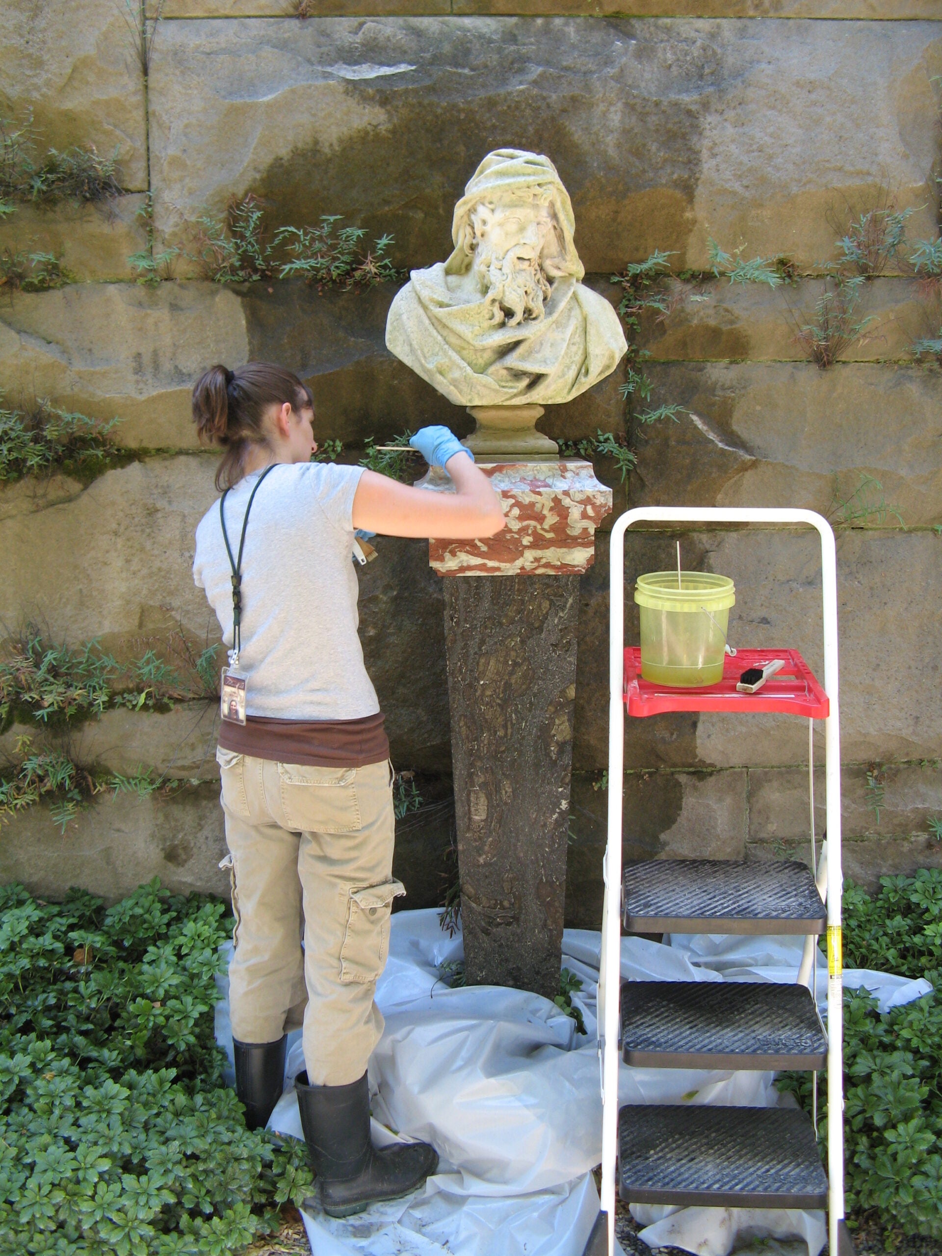 Woman cleans an outdoor bust at Biltmore Estate.