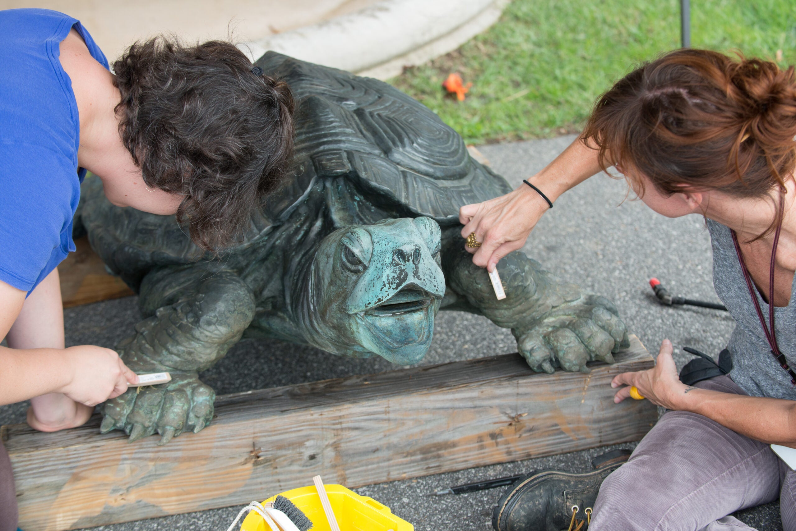 Two women clean a bronze tortoise sculpture at Biltmore Estate.