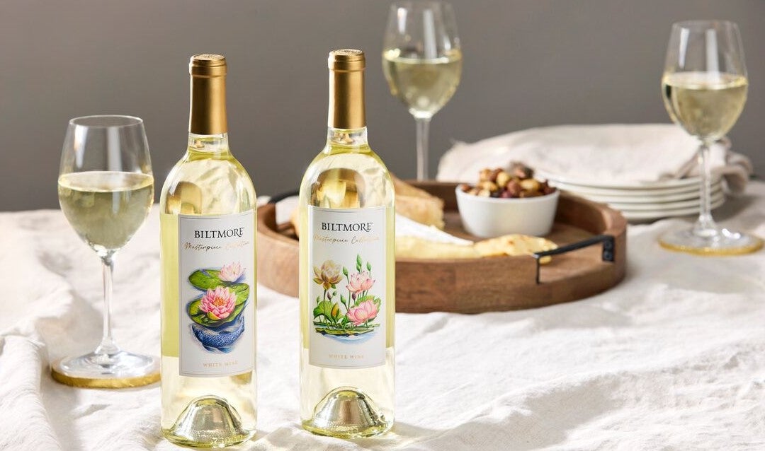 Two bottles of Biltmore Masterpiece Collection white wine on a table with glasses.