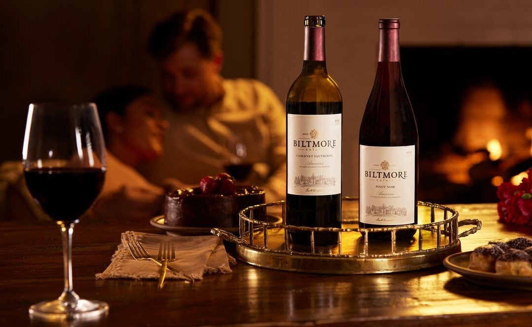 Couple savoring Biltmore wines by a fireplace.