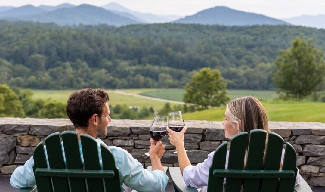 Couple cheers their wine glasses while overlooking mountains at Biltmore