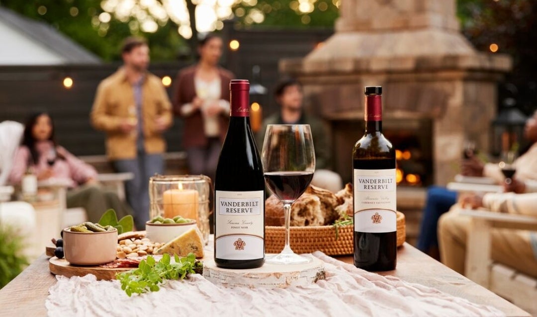 A group of people around an outdoor chimney with Biltmore wines.